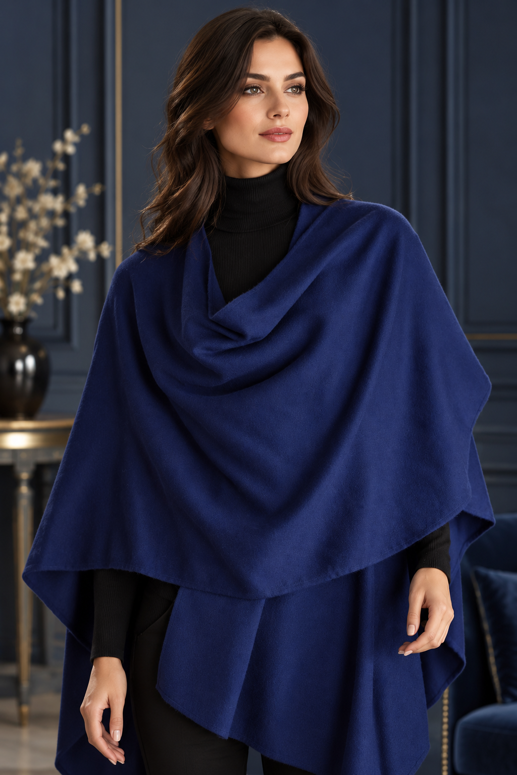 Damenponcho in kräftigem Royalblau mit weichem, fließendem Stoff und elegantem Wasserfallkragen, kombiniert mit einem schwarzen Rollkragenpullover und einer schwarzen Hose.